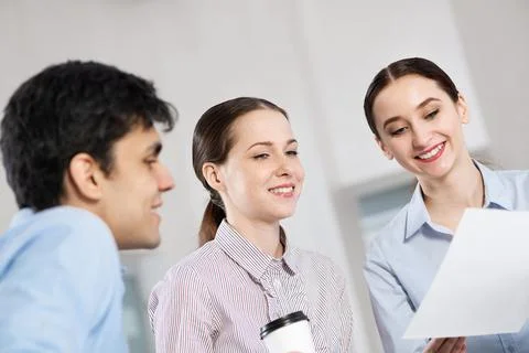 Colleagues discuss documents sitting at a small table Stock Photos