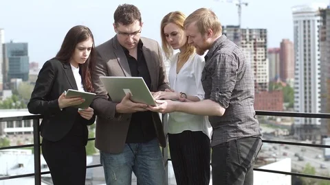 Colleagues discuss work in an informal setting on the roof of an office building Stock Footage 75752669