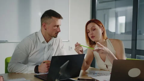 Colleagues discuss work issues sitting at a table in a meeting room Stock Footage 257423080