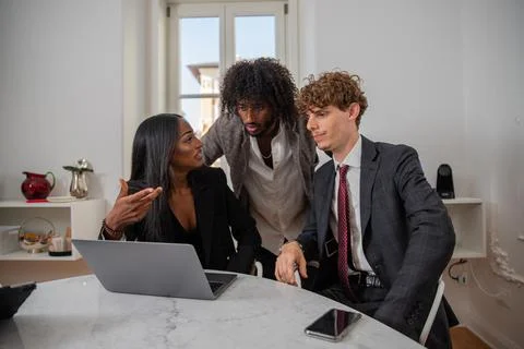Colleagues discuss at work using a laptop, multi-ethnic business group. Foto stock
