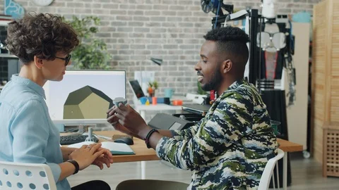 Colleagues discussing 3d printed robot parts in office holding plastic elements Stock Footage 119560271