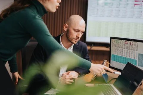 Colleagues discussing data analysis on computer screens in modern office Foto stock
