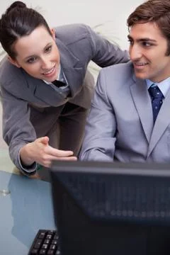 Colleagues in discussion while using computer at office 写真素材