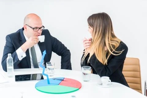 Colleagues drinking coffee in office while discussing new project Stock Photos