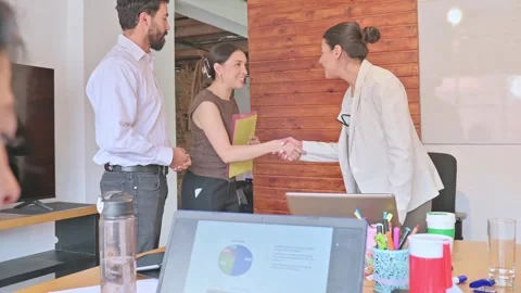 Colleagues exchange a handshake, reviewing documents and discussing ideas. 動画素材 336569935