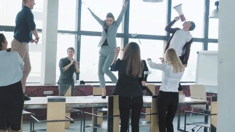 Colleagues fun dancing and jumping on the table, singing in a megaphone and Stock Footage 108370841