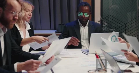 Colleagues group analyze paperwork, talk work together at a team meeting. Stock Footage 242176441