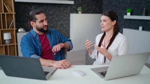 A colleagues have a conversation sitting at the table with laptops in the office Stock Footage 236588289
