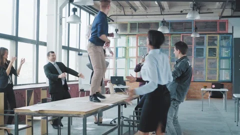 Colleagues have fun dancing on the table in a modern trendy office and celebrate Stock Footage 108366185
