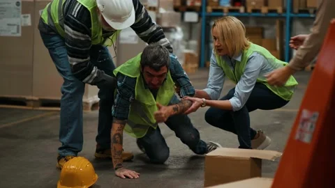 Colleagues help a worker lying down after an accident at the warehouse. Stock Footage 166709363