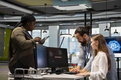 Colleagues helping young worker to block hacking network intrusion Foto stock