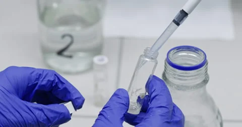 Colleagues insert liquid drop into glass flask in laboratory Stock Footage 274138885