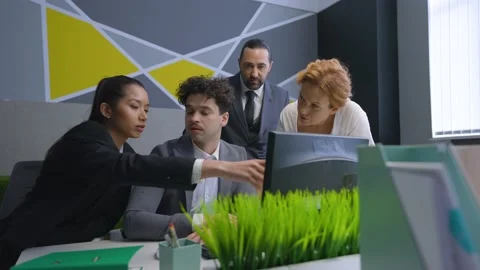 Colleagues in the office gathered at the computer, discussing, solve work issues Stock Footage 233994359