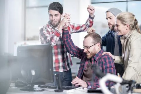 Colleagues in office looking at computer screen cheering Stock Photos
