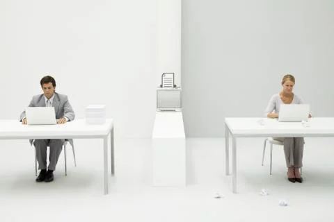 Colleagues in office using laptop computers, printer between them with graphic Stock Photos