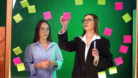 Colleagues pointing at sticky note on green glass board. Stock Footage 342934075