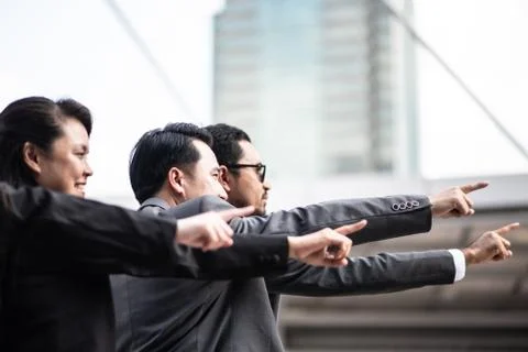 Colleagues Pointing While Standing Against Buildings In City Stock Photos