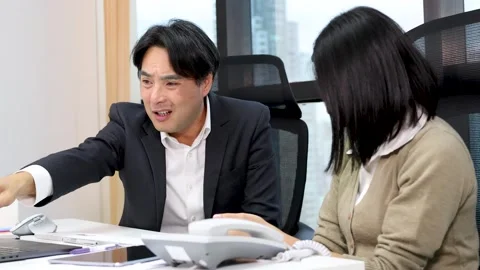 Colleagues React to Surprising News During Office Desk Discussion Video stock 323070598