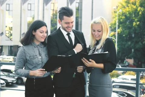 Colleagues reading documents standing on the balcony of the office Stock Photos