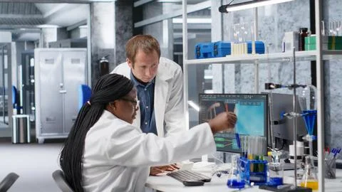 Colleagues in research lab analyzing flasks and chemical samples for experiment 스톡 사진