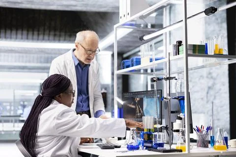 Colleagues in research lab analyzing flasks and chemical samples for experiment 스톡 사진