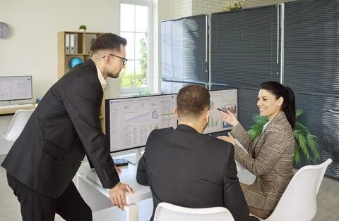 Colleagues review data reports on computer screens during office strategy Stock Photos