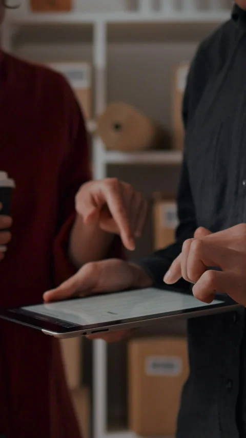 Colleagues review electronic data during discussion in small business wareho Stock Footage 331534292