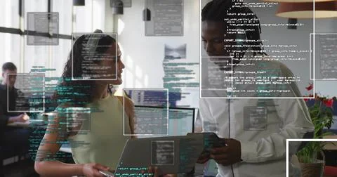 Colleagues reviewing code and data on laptop and tablet in open-plan office,  Stock Photos