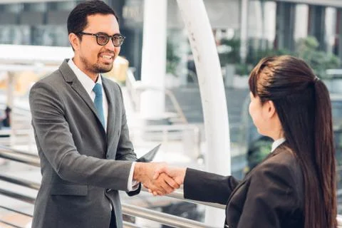 Colleagues Shaking Hands While Standing In Office Stock Photos