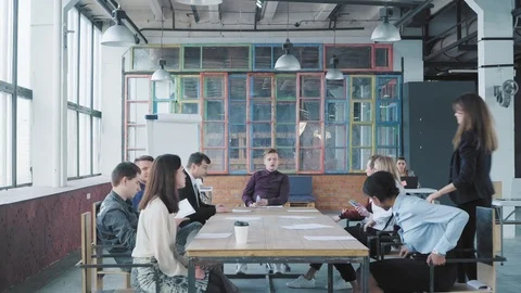 Colleagues sit at a large table and hold a meet up in modern trendy office Stock Footage 108371204