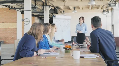 Colleagues sit at the table and discuss the presentation. A female team leader Stock Footage 111590812