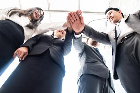 Colleagues Stacking Hands While Standing Against Buildings In City Stock Photos