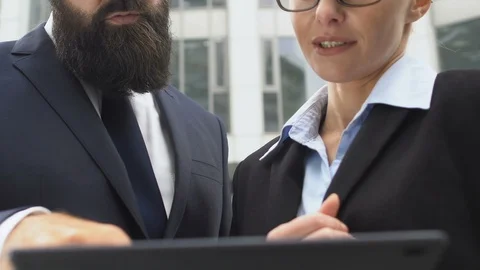 Colleagues with tablet in hands communicating about work project and smiling Stockbeeldmateriaal 119035403