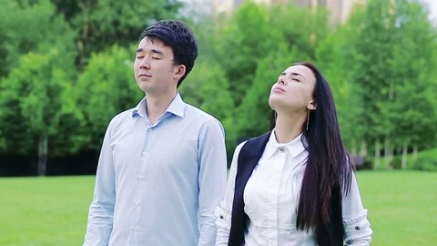 Colleagues taking deep breaths in the park with eyes closed Video stock 77167306