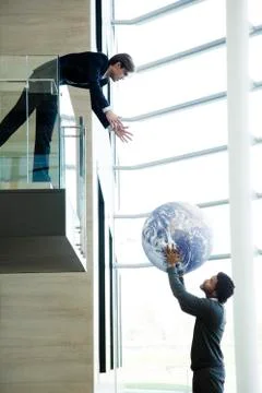 Colleagues throwing ball in lobby Stock Photos