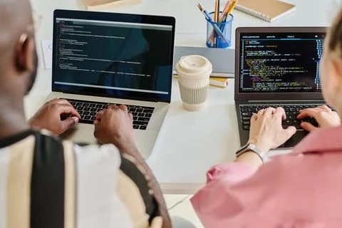 Colleagues typing security codes on laptops Stock Photos