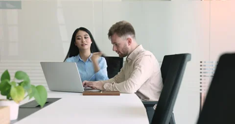 Colleagues using laptop seated at desk in office boardroom Stock Footage 248501757
