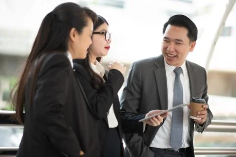 Colleagues Using Laptop While Standing On Bridge In City Stock Photos