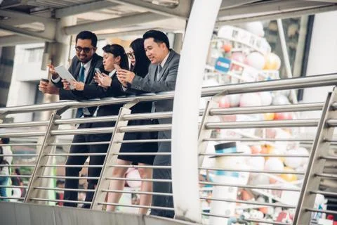 Colleagues Using Mobile Phone While Standing By Railing Stock Photos
