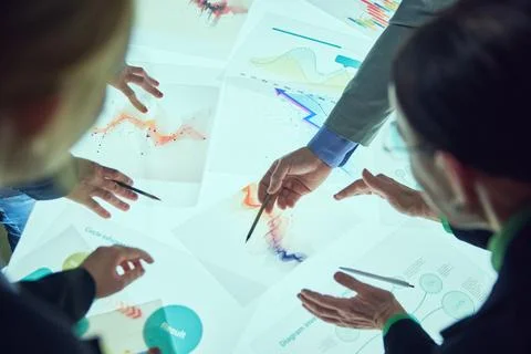 Colleagues working with analytical papers, checking graphs and discussing Stock Photos