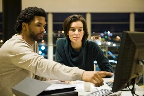 Colleagues working on project together in office at night Stock Photos