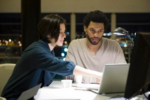 Colleagues working on project together in office at night Foto stock