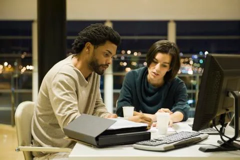 Colleagues working on project together in office at night 스톡 사진