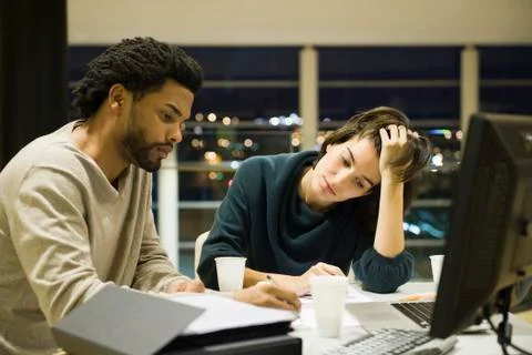 Colleagues working on project together in office at night 스톡 사진