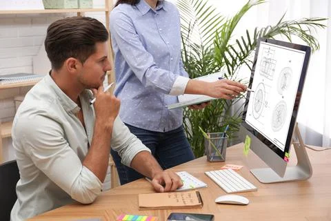 Colleagues working with technical drawing on computer in office Foto stock