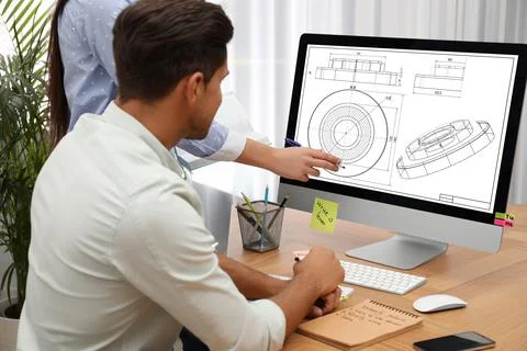 Colleagues working with technical drawing on computer in office Foto stock