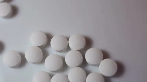Collect small white round pills in a pile. On a white background, close-up, cont Stock Footage 144643592