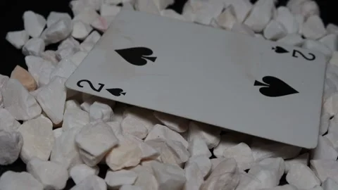 Collectible well-cared-for playing cards on white stones on a black plate rotate Stock Footage 253808564