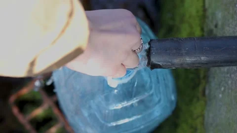 Collecting fresh drinking water in the plastic canister from pipe in the wall. Video stock 171617981