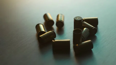 A collection of 9mm bullet shell casings on a dark background Stock Footage